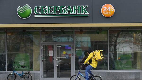 Курьер сервиса доставки Яндекс.Еда у отделения ПАО Сбербанк на одной из улиц в Москве
