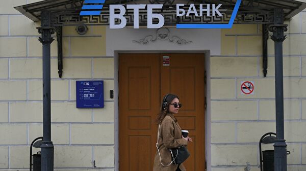 Девушка проходит мимо отделения банка ВТБ на одной из улиц в Москве