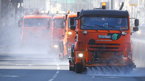 Автомобили коммунальной службы производят мытье асфальтового покрытия с использованием специального моющего средства в Москве