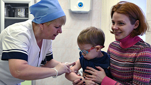 Медицинская сестра делает прививку от кори ребенку в детской поликлинике