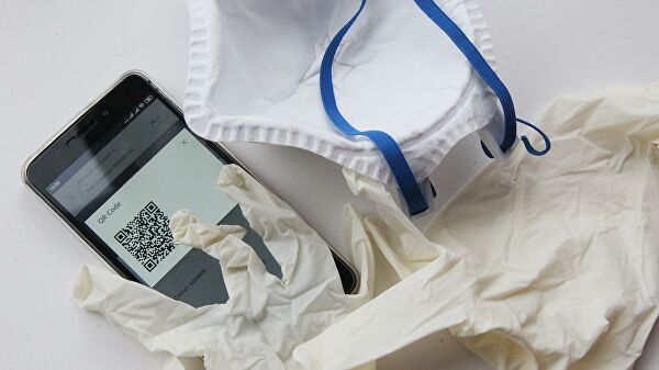 Перчатки, маска и смартфон с QR-кодом для предъявления сотруднику полиции при проверке режима самоизоляци