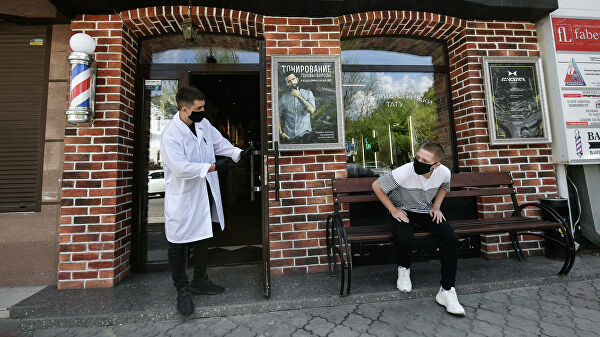 Парикмахер приглашает клиента на стрижку в одной парикмахерских Симферополя