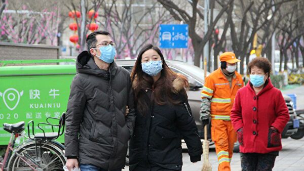 Прохожие в медицинских масках на улице Пекина, КНР