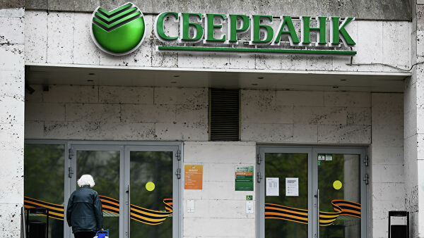Женщина у входа в одно из отделений Сбербанка в Москве